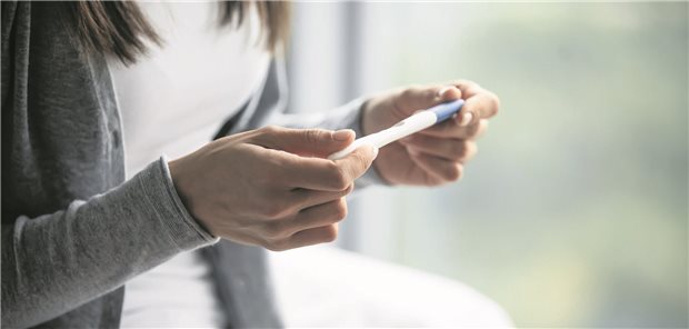 Eine Frau hält einen Schwangerschaftstest in den Händen.