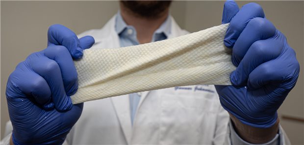 Ein Mann zieht mit beiden Händen einen elastischen Verband in die Länge