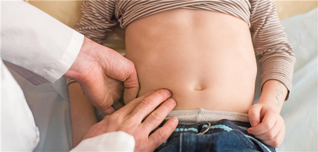 Arzt tastet den Blinddarm eines kleinen Jungen ab. 