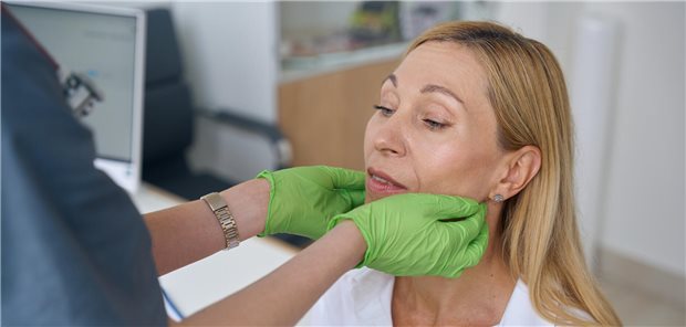 Ärztin palpiert eine Patientin unterhalb der Wangen.