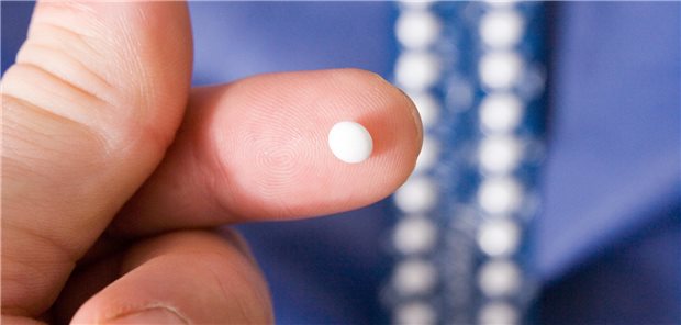 Ein Mann hat eine Pille auf dem linken Zeigefinger.