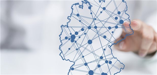 Ein Arzt tippt auf eine Deutschlandkarte mit Punkten und Verbindungen dazwischen.