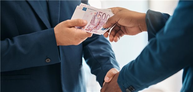 Mann gibt anderem Mann Geld, während sie sich die Hände schütteln.