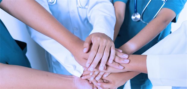 Mehrere Hände unterschiedlicher Gesundheitsberufe übereinander gelegt.