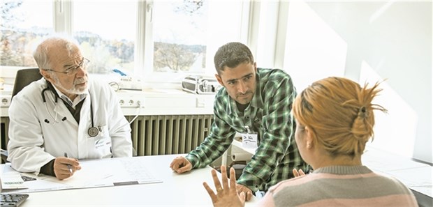 Versorgung von Flüchtlingen: Ein Arzt mit Übersetzer lässt sich Symptome erklären. Wer trägt die Kosten?
