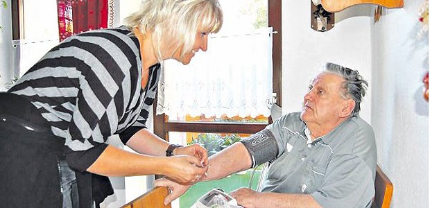 Auf Hausbesuch mit Versorgungsassistentin Manuela Versorgungsassistentin Manuela Jäckel misst den Blutdruck bei einem Patienten.