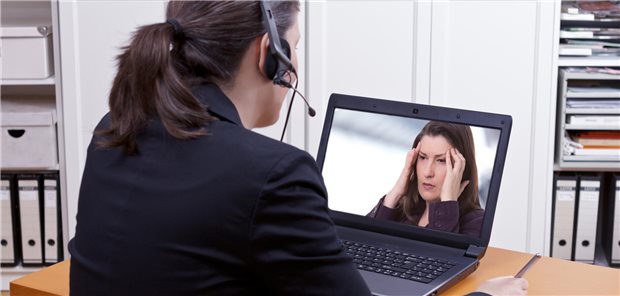 Frau redet mit anderer Frau am Laptop. Zweite hält sich den Kopf.