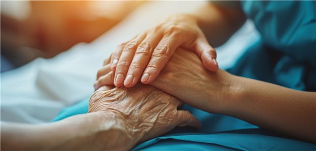 Pflegerin hält die Hand eines Seniors