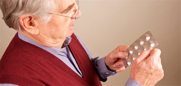 Ein älterer Mann hält ein Blister in der Hand. 