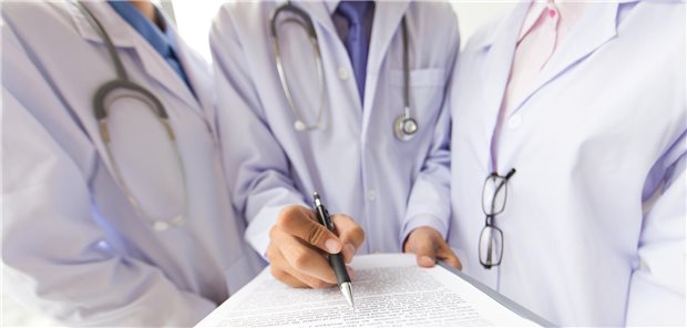 Drei Ärzte stehen zusammen und diskutieren den aktuellen Definitionsvorschlag für eine Difficult-to-Manage (D2M)-Psoriasisarthritis.