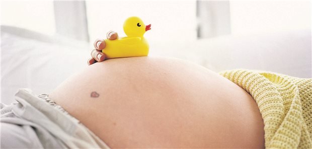 Schwangere Frau mit Quietscheente auf dem Bauch
