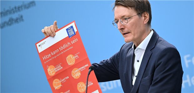 Gesundheitsminister Karl Lauterbach hält am 28. Juli 2023 in der Bundespressekonferenz ein Plakat zum Hitzeschutz hoch.