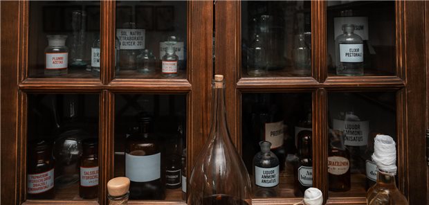 Empty scent bottles in old pharmacy. Wooden antique cupboard for medical drug storage