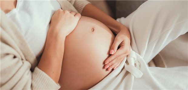 Schwangere Frau hält sich den Bauch.