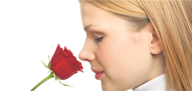 Eine Frau riecht an einer Rose.