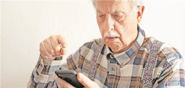 Ein älterer Mann bedient ein Smartphone. 