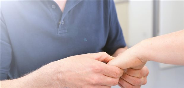 Ein Orthopäde untersucht das Handgelenk eines Patienten.