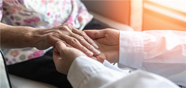 Ein Arzt hält die Hand einer älteren Frau.