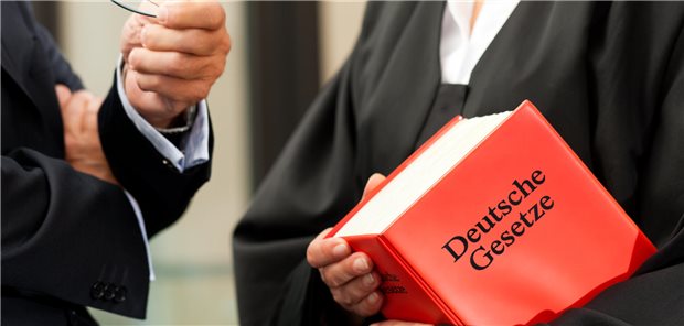 Ein Anwalt hält eine Gesetzessammlung in der Hand.