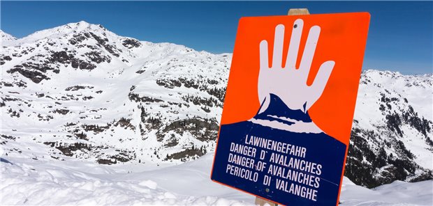 Schild "Lawinengefahr" steht im Schnee in den Bergen