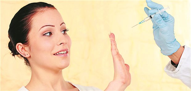 Eine Frau wehrt mit ihrer Hand eine sich ihr nähernde Hand, die eine Impfspritze hält, ab.