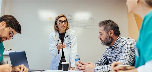 Psychiatrische Kliniken beklagen: Personalplanungsrichtlinie ist zu kompliziert Diskussion: eine Frau mit Stethoskop und Kittel tseht vor zwei Männern und einer weiteren Frau; sie scheinen in eine Diskussion vertieft zusein.