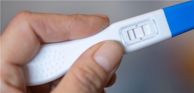 Eine Frau hält einen Schwangerschaftstest in der Hand