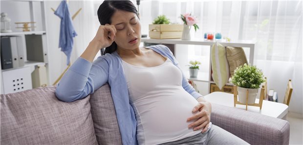 Eine schwangere Frau sitzt auf einem Sofa.