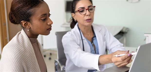 Schwarze Patientin mit weißer Ärztin im Gespräch.