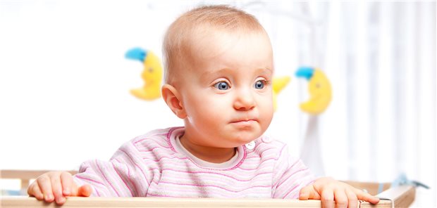 Kleinkind schaut über die Bettkante. 