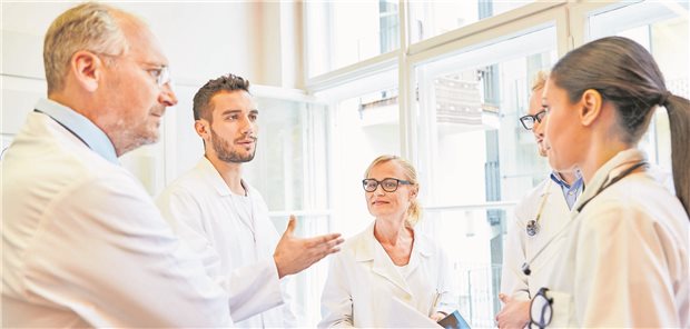 Ärzte verschiedenen Alters stehen zusammen in einem Kreis