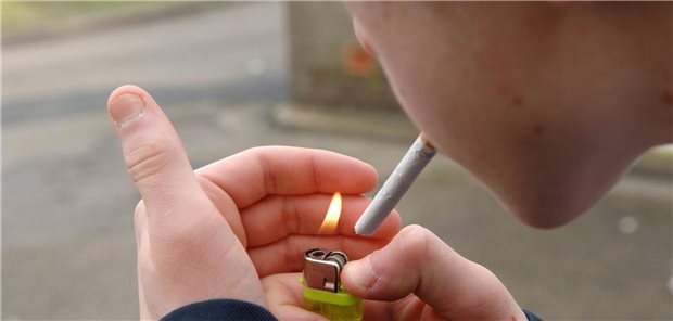 Ein Teenager zündet sich eine Zigarette mit einem Feuerzeug an. 