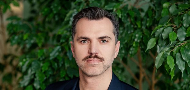 Manuel Nothelfer steht vor einer Blätterwand und schaut in die Kamera.