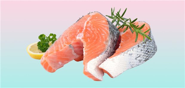 Zwei Lachsfilets mit Rosmarin und einer Zitrone liegen auf einem zweifarbigen Hintergrund.