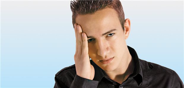 ein junger Mann hällt sich die Hand an die Schläfe