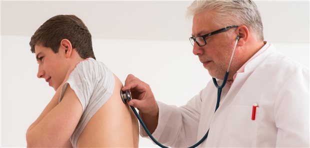 Arzt hört einen Teenager mit dem Stethoskop ab. 