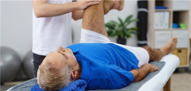 Ein älterer Mann lässt sein Knie mit Totalendoprothese wegen postoperativer Instabilität beim Physio-Therapeuten behandeln.