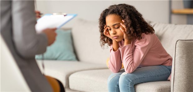 Eine junge Patientin, die auf einer Couch in der Praxis ihres Psychologen sitzt und mit diesem über ihre Probleme spricht.