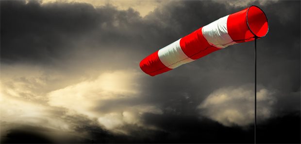 Eine rot-weiße Windhose vor Gewitterwolken.