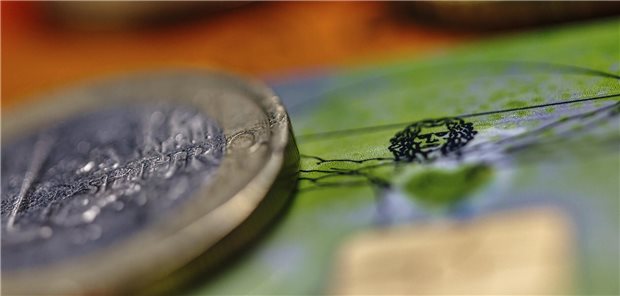 Das Foto zeigt eine 1-Euro-Münze, im Hintergrund ist das Motiv des vitruvianischen Menschen von Leonardo da Vinci auf einer GKV-Versichertenkarte zu sehen.