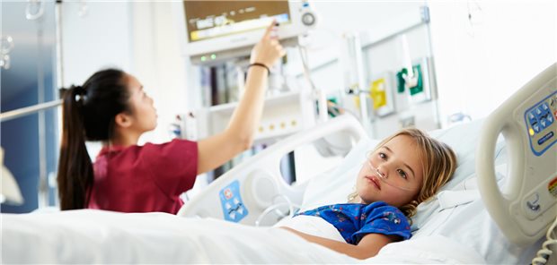 Ein junges Mädchen das von einer Krankenschwester auf der Intensivstation versorgt wird.