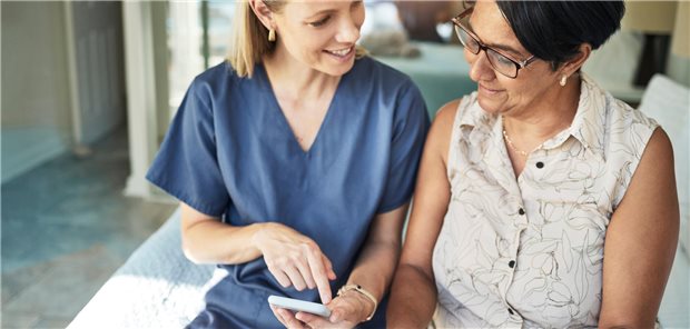 Eine junge MFA zeigt einer älteren Frau eine Anwendung auf einem Smartphone.