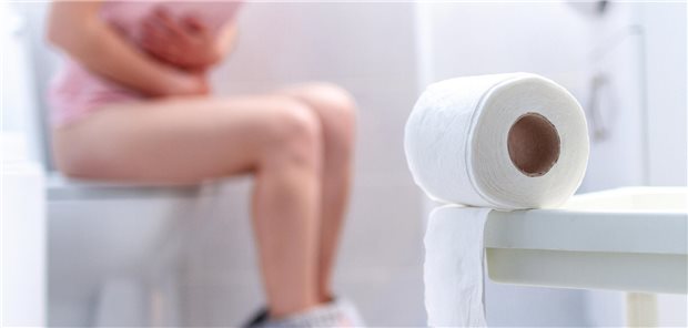 Eine Frau, die unter Reisediarrhö leidet, sitzt auf der Toilette.