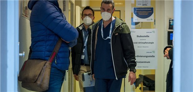 Corona-Impfstart im Saarland macht Gesundheitsministerium „stolz“ Zwei Mitarbeiter des Impfteams tragen eine Kühlbox mit Impfstoff aus der Stabsstelle des saarländischen Gesundheitsministeriums: Die Landesgesundheitsministerin ist mit dem Start zufrieden. Diese Einschätzung wird nicht von allen Saarländern geteilt.