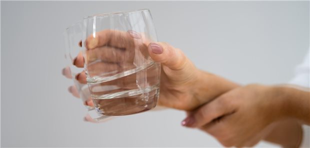 Eine Frau hält ihre zitternde Hand fest