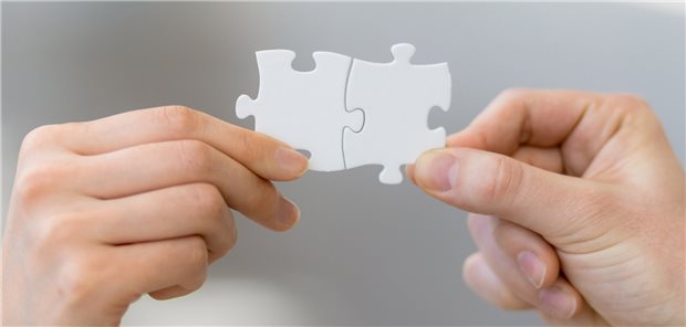 Hände fügen zwei Puzlzestücke zusammen.