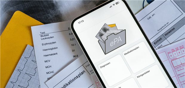 Ein Smartphone, auf dem gerade eine elektronische Patientenakte angezeigt wird, liegt auf medizinischen Dokumenten.